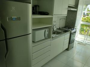 嘎林海斯港Palm Village Acqua - Apartamento Premium - Em frente à piscina - Porto de Galinhas的白色的厨房配有冰箱和微波炉。