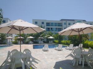 嘎林海斯港Palm Village Acqua - Apartamento Premium - Em frente à piscina - Porto de Galinhas的一组椅子和遮阳伞,位于游泳池旁