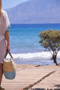 阿基欧斯尼古拉斯The Island Concept Luxury Boutique Hotel Heated Pool的一名妇女带着篮子在海滩上行走