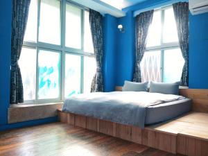 台南麦克阿舍的一间拥有蓝色墙壁的卧室和一张窗户床