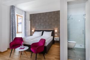 托尔明Hotel Dvorec的酒店客房,配有一张床和两张粉红色的椅子