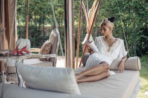 湄南海滩Khwan Beach Resort - Luxury Glamping and Pool Villas Samui - Adults Only - SHA Extra Plus的坐在秋千上读书的女人