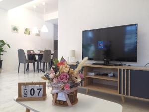 诗巫Merdeka One Homestay 8pax 4Rooms的客厅配有电视和鲜花桌