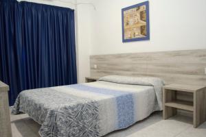 贝尼多姆Pensión Pardo的一间卧室配有床和蓝色窗帘