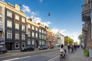 阿姆斯特丹Huygens Place Amsterdam的骑着自行车在街道上与建筑物在一起的女人