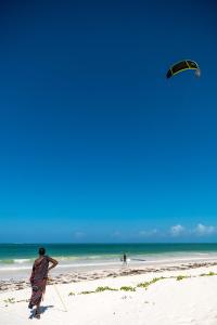 帕杰Hakuna Majiwe Beach Lodge的一名在海滩上放风筝的人
