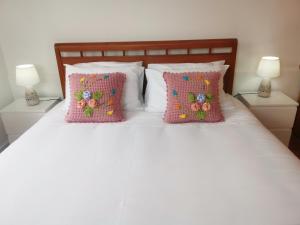 桑塔纳Casa do Curral Velho的一张带两个粉红色枕头和两盏灯的白色床