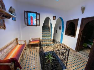 舍夫沙万Dar Essaouyry的一间带楼梯和彩色玻璃窗的客厅