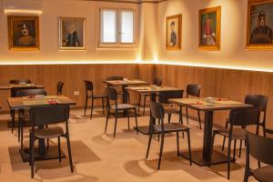 弗留利地区圣达尼埃莱Hotel Residence Dolcenero的用餐室配有桌椅,墙上挂有图片