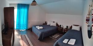 CupşeniAgropensiunea Pe Poderei的一间卧室设有两张床和蓝色窗帘