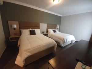 危地马拉L'Aurora Inn的两张位于酒店客房的床,配有两张sidx sidx单人床