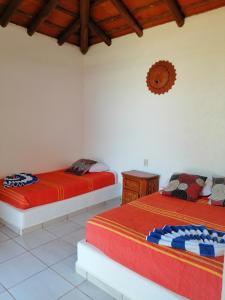 特隆戈内斯Casa La Quinta Ola的白色墙壁客房的两张床