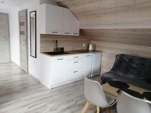KarsinPAKLADA 3 Pokój typu studio的厨房配有白色橱柜和桌椅