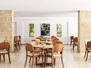 罗德镇Esperia City Hotel的用餐室配有桌椅,墙上挂有绘画作品