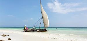吉汶瓦ARYA Boutique Resort的和水里的人一起在海滩上航行的帆船