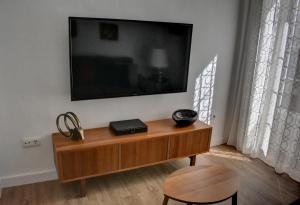 赫雷斯-德拉弗龙特拉Apartamentos Las Naranjas的墙上的平面电视,配有木桌