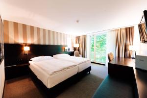 温特图尔Park Hotel Winterthur的酒店客房设有一张大床和一张书桌。