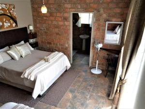 LichtenburgEdenville Guesthouse的一间卧室设有一张床和砖墙