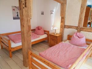 巴特罗森菲尔德Große Bauernhaus Ferienwohnungen bis 100qm mit Grillhütte & Garten & E-Bike-Verleih的一间客房配有三张双层床和粉红色床单。