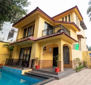 果阿旧城VILLA M - LAGOON 4 CALANGUTE GOA 3BHK, Pool Facing, Near Beach, Free Breakfast, Free WIFI and Well Located的一座黄色的房子,前面有一个游泳池