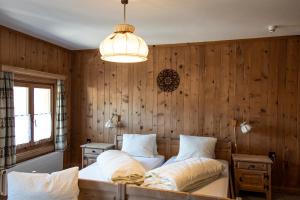 圣玛利亚瓦尔姆斯塔尔Alpina B&B Apartments的卧室配有木墙内的两张床