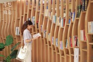 台中市梦想12旅店 的站在图书馆看书的女人