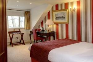 罗奇代尔Broadfield Park Hotel的配有一张床、一张桌子和一张桌子的酒店客房