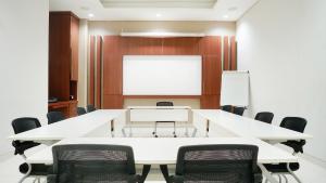 日惹Grand Omah Sastro的一间会议室,配有白色的桌椅和白色的板