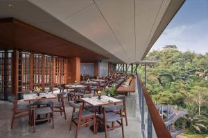 万隆The Gaia Hotel Bandung的阳台餐厅,配有桌椅