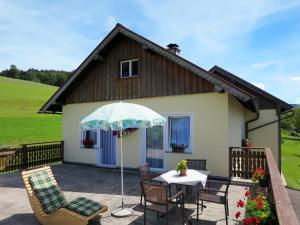 OberwangHoliday Home Mayrhofer - MON240 by Interhome的庭院配有桌椅和遮阳伞。