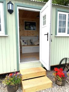 珀斯Remarkable Shepherds Hut in a Beautiful Location的绿白的棚子,有门和花