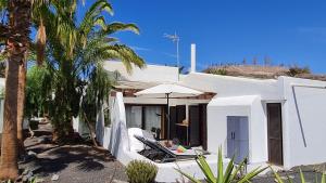 莫罗德哈布雷Casa EL JARDIN的白色的房子,配有椅子和遮阳伞,棕榈树