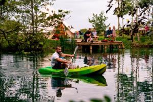 雷克瑟姆Arcadia Safari Tent in private 5 acre field的水里一个穿着绿色皮艇的人