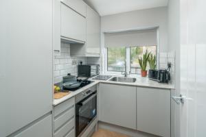 斯蒂夫尼奇Skyline Serviced Apartments - Flat B Rockingham Way的厨房配有白色橱柜和水槽