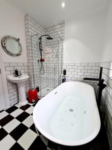 朴次茅斯Southsea Royale James Bond 3 bed Cool Penthouse, seafront parking的浴室配有白色浴缸和水槽