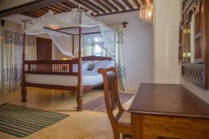 拉穆MANDA ISLAND Private Villa的一间卧室配有一张天蓬床和一张木桌