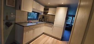 DoornspijkChalet 11, in het bos的小厨房配有白色橱柜和水槽