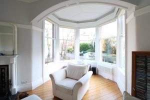 格拉斯哥Two Bed Holiday Home in Glasgow的客厅配有白色椅子和大窗户