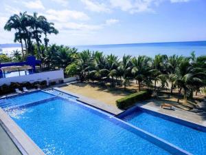 通苏帕Resort Playa Azul 3 Dormitorios的一座棕榈树和海洋的大型游泳池