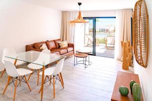 Parque HolandesShambhala Fuerteventura的客厅配有玻璃桌和白色椅子