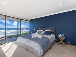 仙女港Iluka的卧室设有蓝色的墙壁和一张享有海景的床。