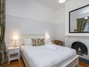 仙女港Eamont On Sackville的白色卧室设有白色的床和壁炉