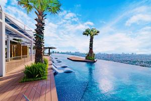 胡志明市La Vela Saigon Hotel的一座带棕榈树的无边泳池