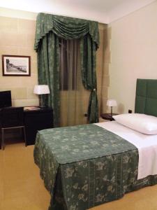 锡拉库扎多莫斯马里阿贝尼西尔酒店的一间卧室配有一张床、一张书桌和一个窗户。