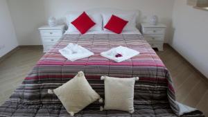 阿尔贝罗贝洛多莫斯公寓式酒店的一张配有红色和白色枕头的大床