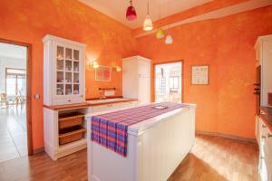 卢瓦尔河畔圣西CoTTAGE LA VILLA BOLERO的一间厨房,里面拥有橙色的墙壁和岛屿