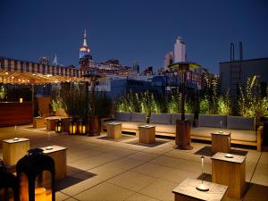 纽约The Moore的一个带桌子和长凳的屋顶露台,享有城市天际线