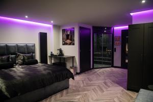 斯赫拉芬赞德Royal Suite的一间紫色照明的卧室、一张床和一张书桌
