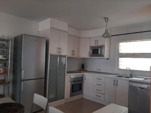 卡门港奥瑞玛公寓的厨房配有白色橱柜和不锈钢冰箱