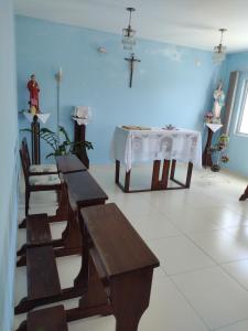 瓜拉图巴Stela Maris的一间设有长椅和桌子的房间,墙上有十字架
